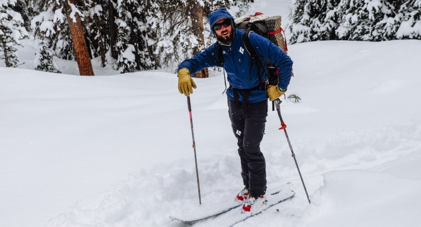 A person wearing winter gear stands on skis in a snowy landscape.